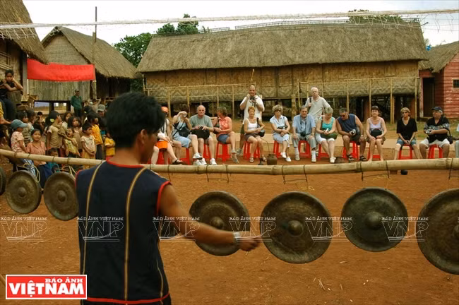  Des touristes écoutent une démonstrations de gongs dans un village.