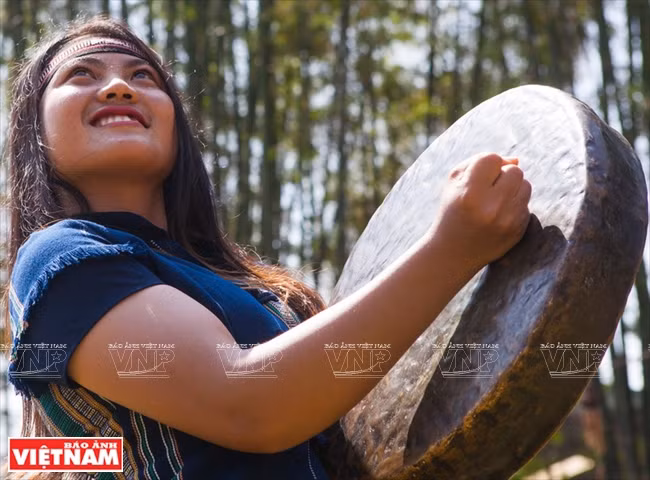 Jeune fille Xe Dang jouant du gong lors d'une cérémonie de mise en place de conduites d'eau. 