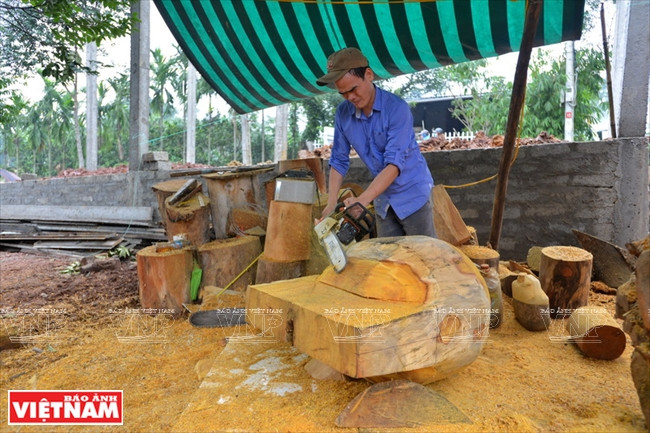 Un artisan utilise une grande scie pour découper le bois. Photo : Thanh Hoà