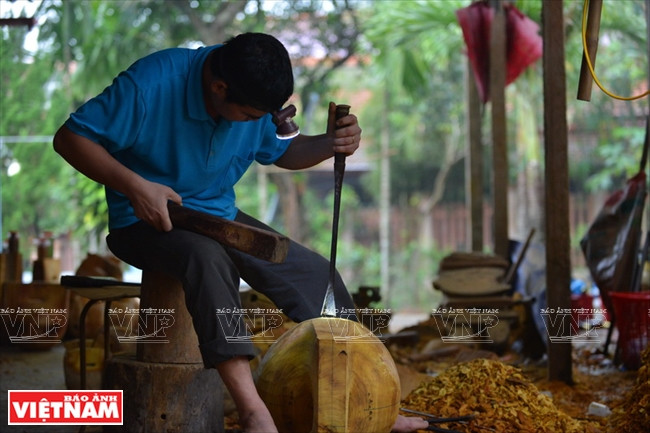 Lartisan utilise une lampe frontale pour percer la caisse de résonnance. Photo : Thanh Hoà