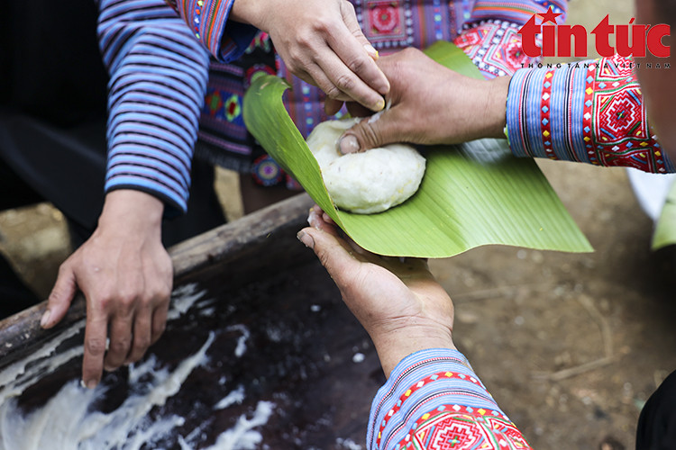 Les femmes prennent la relève. Tout d’abord, elles façonnent le gâteau en cercle, puis l’enveloppent de feuilles de bananier chauffées au feu. Ensuite, elles pressent doucement le gâteau avec leurs mains pour créer une forme ronde comme la lune et le soleil. Photo: VNA