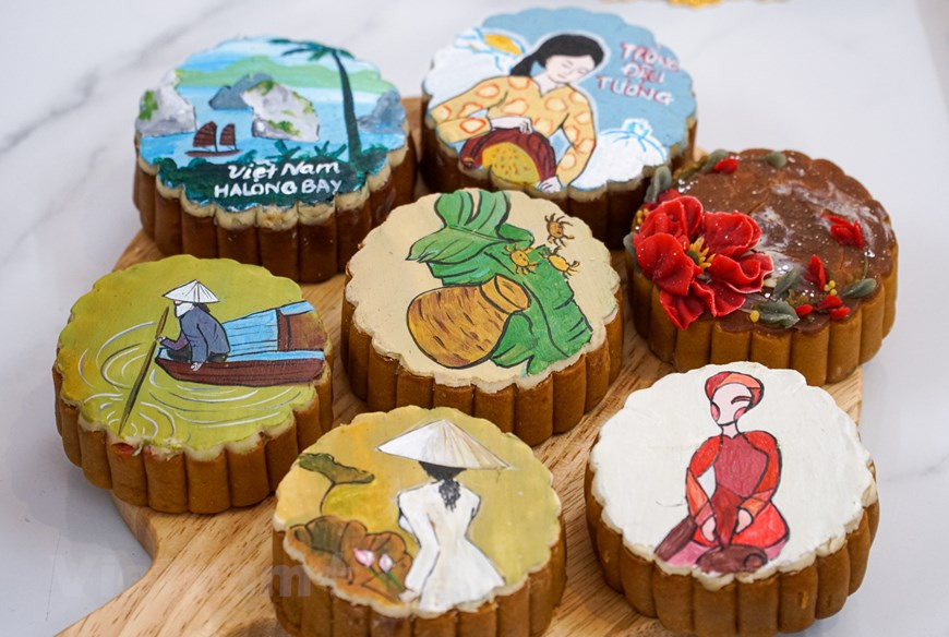 Des images caractéristiques de la culture vietnamienne comme l’ao dài, la baie de Ha Long, la fleur de lotus,... décorent ses gâteaux de lune. Il y a une partie émerveillement quand des enfants ou une personne découvrent ces pâtisseries. Photo: VietnamPlus