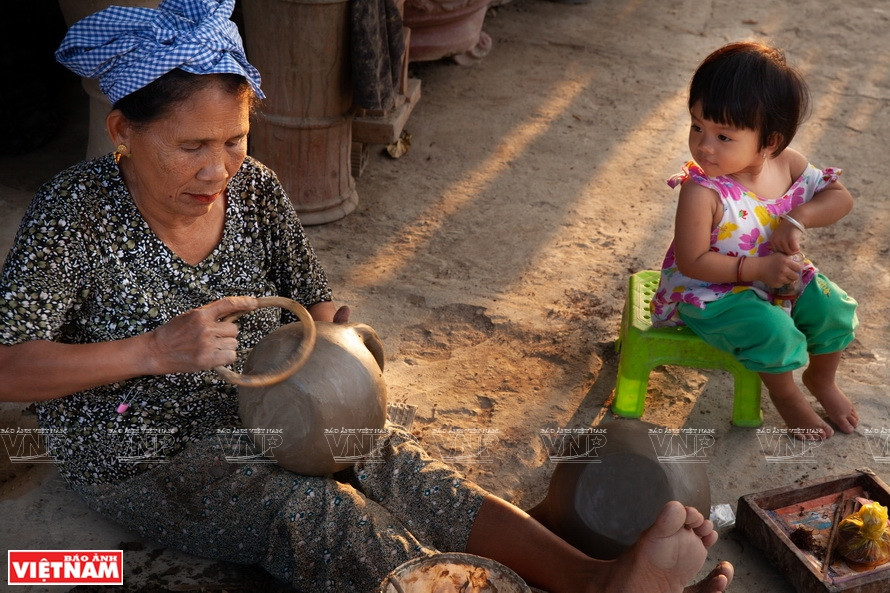 Des artisans corrigent l'aspect du produit de poterie, après le moulage et le séchage au soleil.