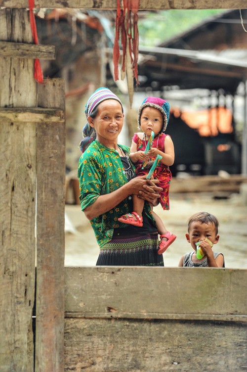 Des enfants et leur grand-mère devant leur maison dans la commune de Pho Cao.