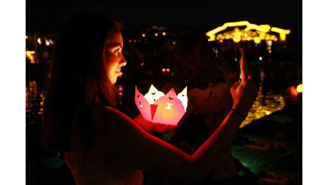 Un groupe de touristes étrangers captent leur image avec de beaux sourires sur la rivière de Hoài. Puis ils lâchent des lanternes sur cette rivière dans le souhait de la paix et de la chance.
