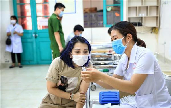 Un agent de santé du Centre médical de l’arrondissement de Hoan Kiêm présente le vaccin Moderna à un habitant. Photo : VNA