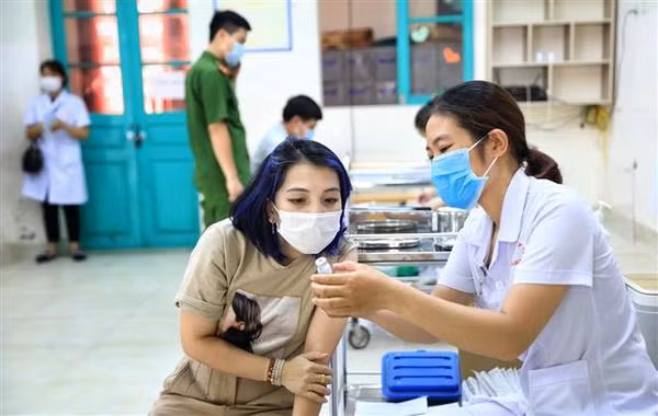Un agent de santé du Centre médical de l’arrondissement de Hoan Kiêm présente le vaccin Moderna à un habitant. Photo : VNA