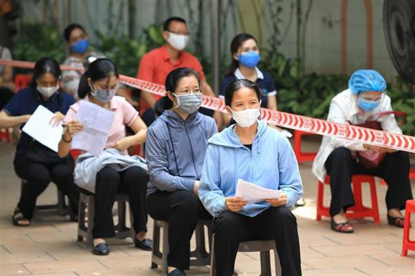Les habitants de l’arrondissement de Hoan Kiêm respectent la garantie de la distance aux points de vaccination. Photo : VNA