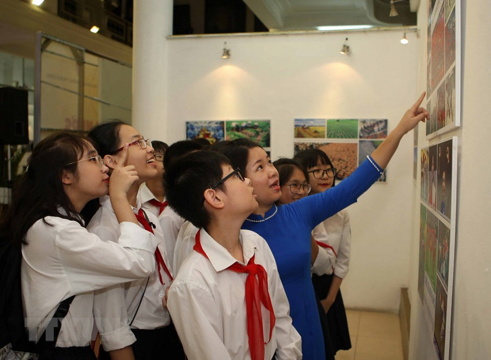 L’enseignante et les élèves du collègue Trung Vuong (Hanoï) contemplent des photos lors de l’exposition. 