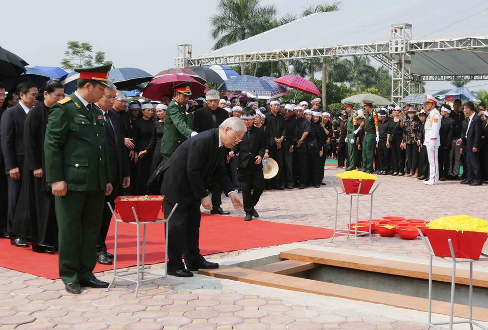 Le secrétaire général Nguyen Phu Trong jette une poignée de terre dans la tombe de l'ancien secrétaire général Do Muoi.