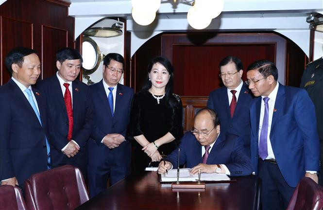 Le Premier ministre Nguyen Xuan Phuc écrit sur le livre des visiteurs du bateau-musée Aurore