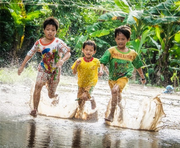 Enfants jouant sur une route inondée à Tay Ninh