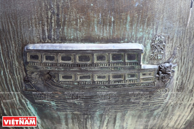 Symbole d'un long bateau sur l'urne Nhân. Il s'agit d'un navire en bois de haute qualité, doté d’un pont (réalisation exceptionnelle de l'industrie navale du Vietnam pendant la dynastie des Nguyên), construit sous les règnes des rois Gia Long et Minh Mang. Ce bateau était pour le roi, la famille impériale ou les mandarins militaires.