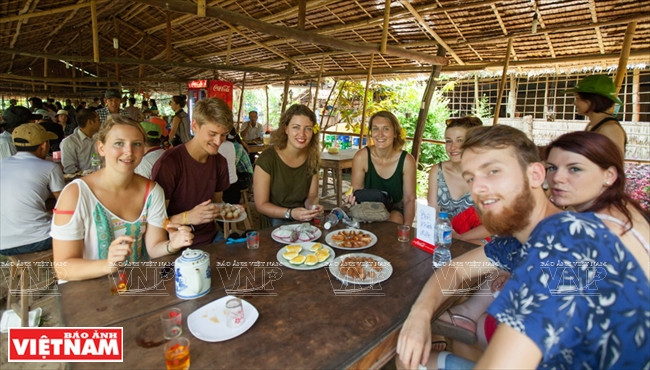 Les touristes étrangers bénéficiant du thé et des fruits dans le jardin Ut Hiên. 
