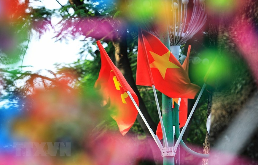 Les couleurs rouge et jaune des drapeaux nationaux se mêlent sous le soleil doré du ciel d'automne de Hanoï. Photo: VNA