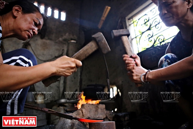 Deux artisans donnent en alternance des coups de marteaux.