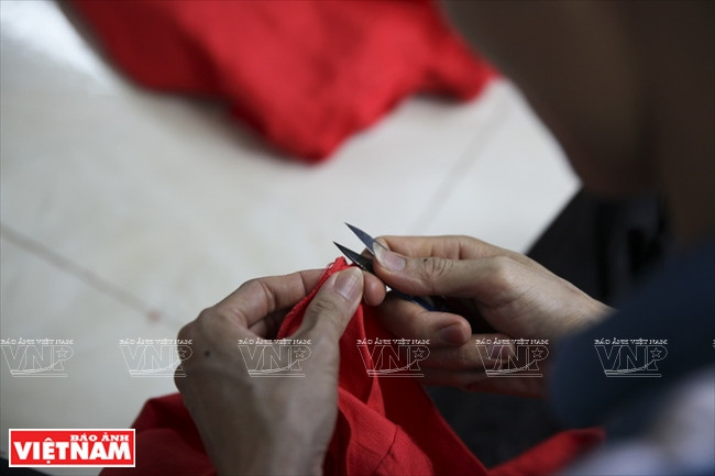Le couturier vérifie la broderie sur la bande de bordure latérale de l’ao dai. 
