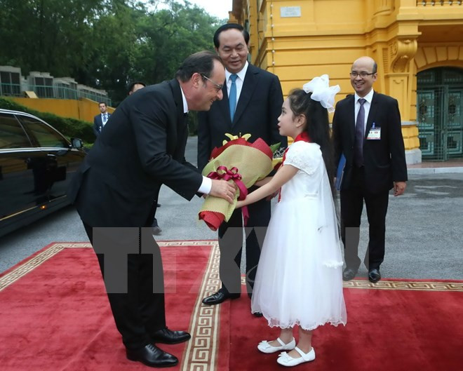 Une petite fille vietnamienne offre un bouquet de fleurs au président François Hollande. 