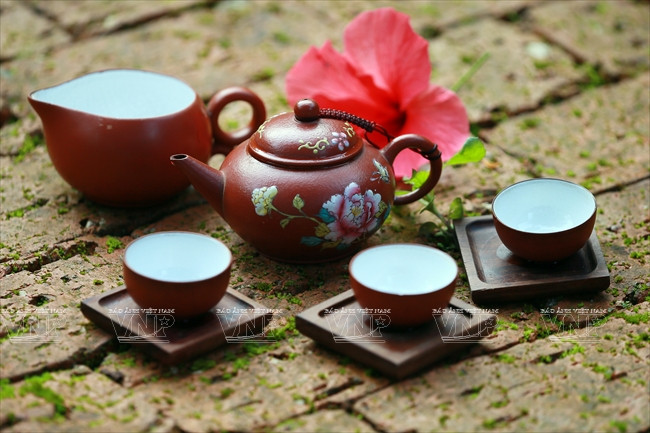 Un service à thé comprend un pot, une grande tasse et trois petites tasses.