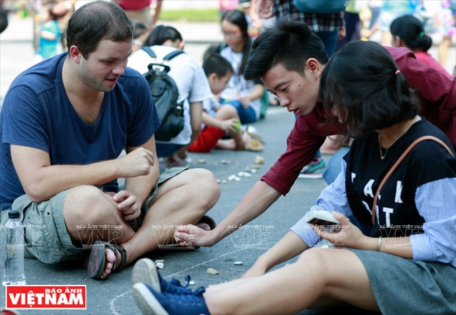 Un membre du club My Hanoï apprend à un touriste étranger à jouer à la marelle.