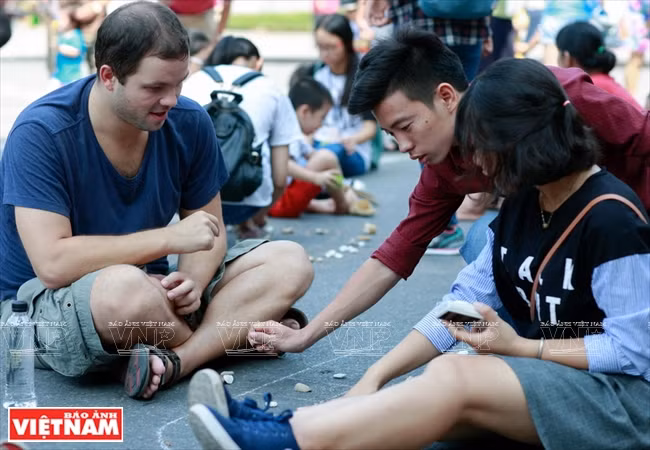Un membre du club My Hanoï apprend à un touriste étranger à jouer à la marelle.