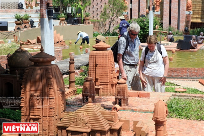 Des visiteurs étrangers admirent des représentations de merveilles du monde en terre cuite.