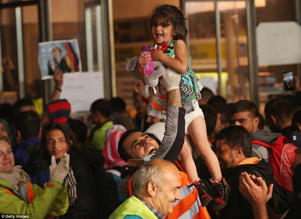 Un bénévole allemand porte un enfant réfugié dans les applaudissements pour saluer des centaines de réfugiés à la Gare centrale de Munich.