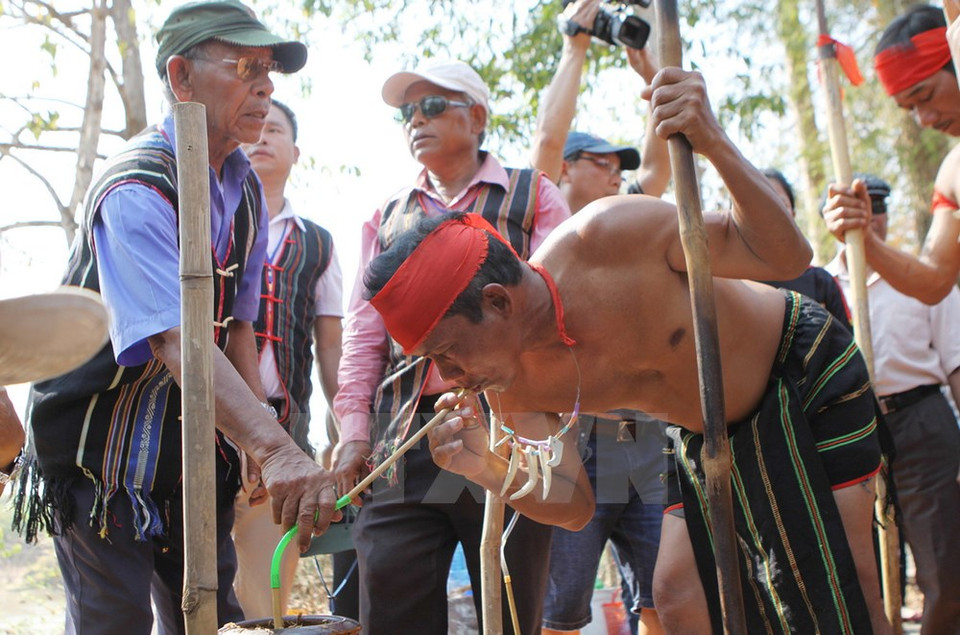Un homme boit de Rượu cần (alcool de riz à siroter avec un chalumeau de bambou). 