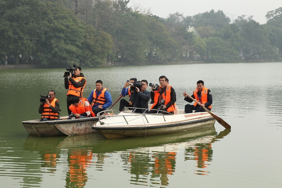  Le photojournaliste Tri Dung de la VNA et un journaliste de la Télévision nationale du Vietnam au lac Hoan Kiem (Epée restituée) pour couvrir le programme "Xuan que huong" (Printemps au pays natal) en 2019. Photo : VNA