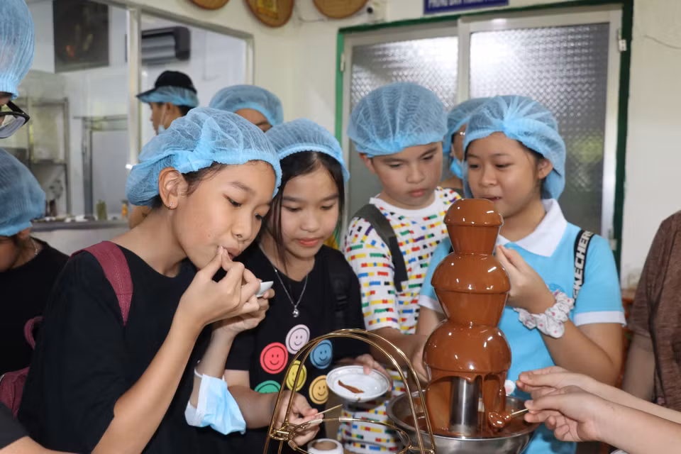 Les jeunes touristes aiment déguster du chocolat frais produit au chocolaterie de la Sarl de cacao Xuan Ron Cho Gao. Photo de: TTXVN