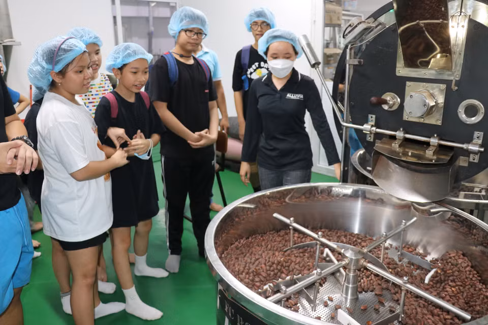Les touristes découvrent le processus de torréfaction des fèves de cacao pour produire du chocolat. Photo:VNA