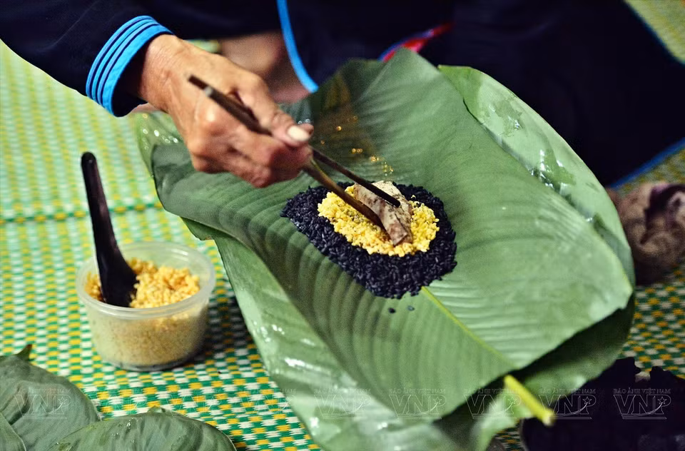 Pour commencer, il faut étaler les feuilles. Ensuite, disposer une couche de riz, puis deux morceaux de viande, une couche d’haricot mungo, et recouvrir d’une autre couche de riz. Habituellement, le bánh chưng noir sera cuit pendant environ 12 heures. Sa forme cylindrique constitue aussi une particularité de cette spécialité culinaire des Tày de Bac Hà.