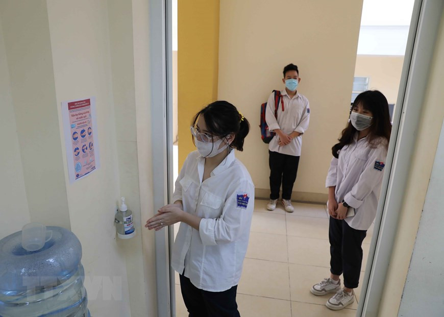 Des élèves doivent se laver les mains avec du gel hydro-alcoolique avant d'entrer en classe. Photo: VNA