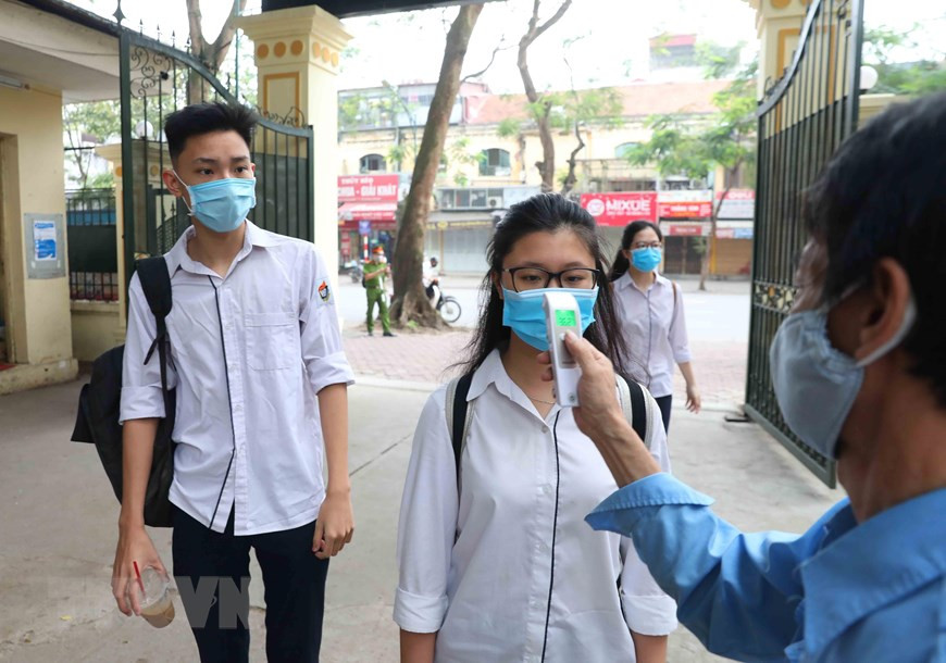 Des élèves du lycée Viet Duc à Hanoï se font contrôler la température corporelle avant d'entrer dans l'école. Photo: VNA