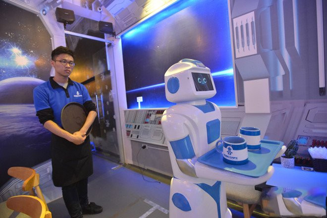 L’employé donne l’ordre au robot de servir les boissons à chaque table.