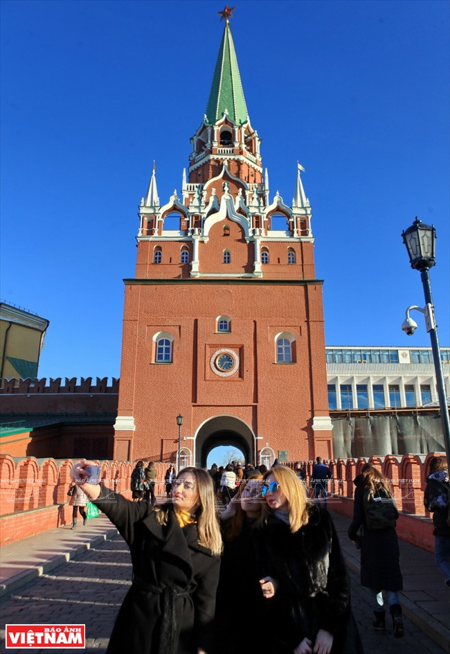 Les touristes posent pour photos souvenirs devant la tour Troitskaya de Kremlin.