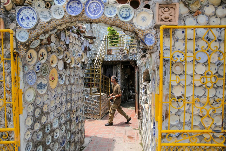 Sa maison est, à première vue, une simple petite bâtisse située dans une ruelle. En s’approchant, on aperçoit la clôture de la maison décorée par des morceaux de céramiques. Après avoir franchi la porte d’entrée, le visiteur est surpris par la façade impressionnante de la maison sur laquelle reposent des rangées d’assiettes, de bols, des petites jarres et de vases fixés solidement sur le mur par de la colle. Le salon de la maison est, lui aussi, hors du commun, outre les murs couverts de porcelaines, trois piliers sont couverts de pièces de monnaie et de gros boutons de chemise. Photo : VietnamPlus