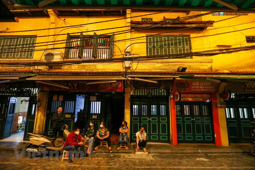  La fermeture temporaire des commerces est nécessaire pour prévenir la propagation du Covid-19. Certains gens portent des masque de protection devant leur maison et restaurant. L’ambiance est des plus calmes. Un habitant local a partagé : "Jamais je n'ai vu la rue Ta Hiên aussi calme ! C'est un spectacle rare car la zone est connue sous le nom de +rue qui ne dort jamais+". Tout le monde fait contre mauvaise fortune bon cœur car cette situation, bien évidement, n’est que temporaire. Tout devrait rentrer normalement dans l’ordre dans les semaines à venir en vue de reprendre leurs acivités professionnelles. Photo: VietnamPlus 