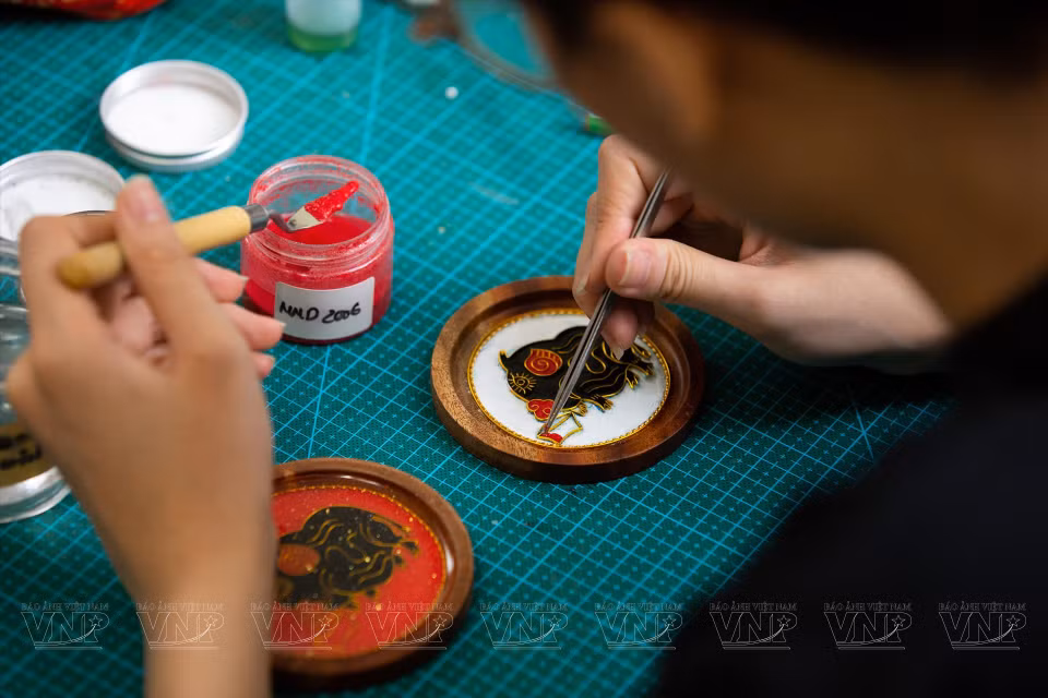 Après avoir achevé le cadre d'une peinture ''Hoa kim sa'', fait de cuivre avec de motif spécifique, le fabricant commence à peindre le sable en différentes couleurs.