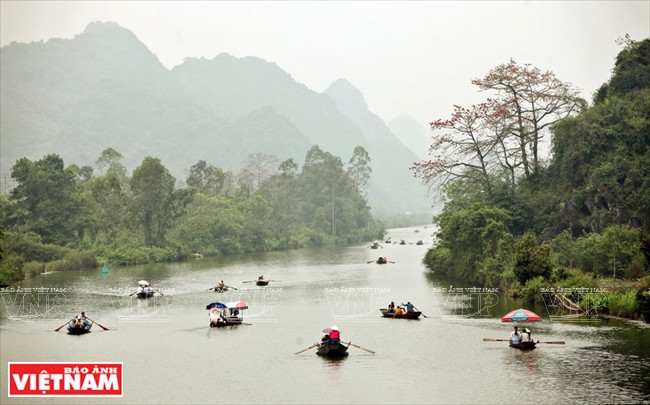 Barques de visiteurs empruntant la rivière Yên, qui serpente au pied des montagnes.