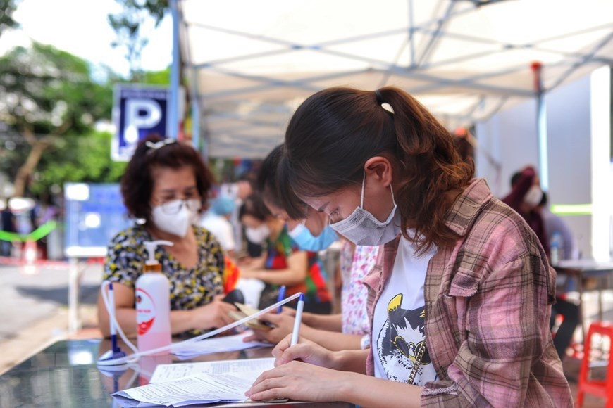 Des habitants du quartier de Pham Dinh Hô, arrondissement de Hai Ba Trung, font leur déclaration de l'état de santé avant la vaccination. Photo : VNA