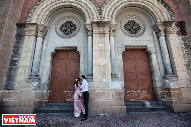 Un couple prend des photos à côté de la Cathédrale Notre-Dame de Saigon.