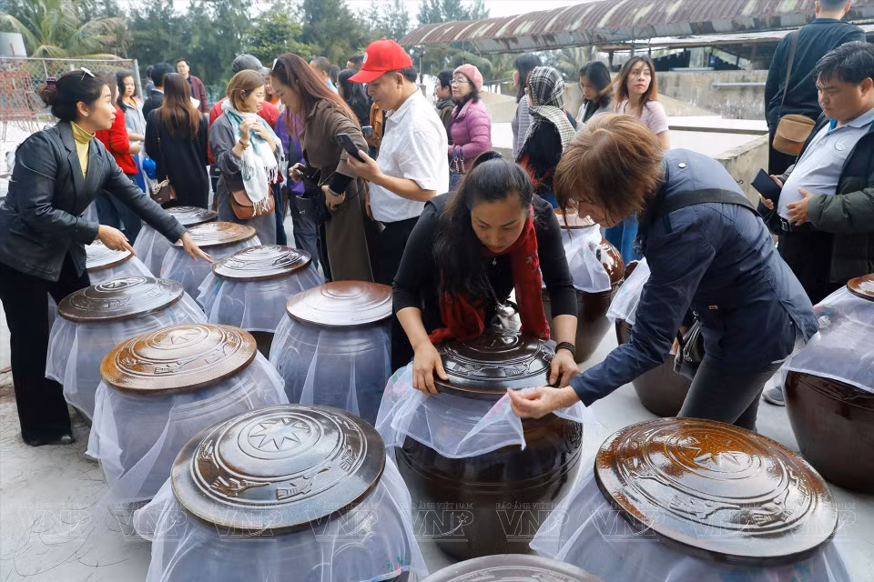 Touristes visitant un établissement de production de sauce aux palourdes de Con Den.
