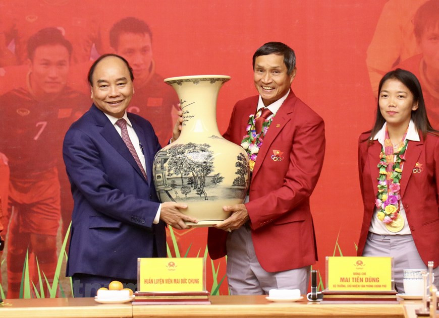 L’entraîneur de la sélection féminine de football Mai Duc Chung reçoit le cadeau du Premier ministre.