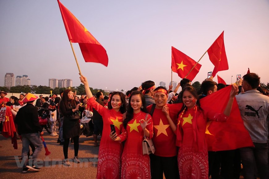 Pour encourager l'équipe national, les filles portent l'"ao dai" (tunique traditionnelle vietnamienne) avec l'étoile jaune sur fond rouge. Photo: Vietnam+