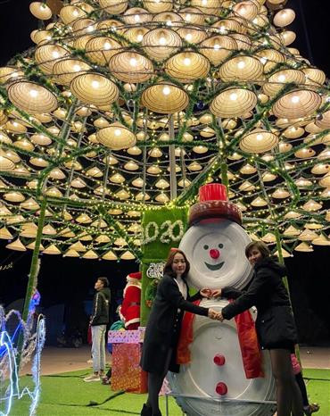 Des jeunes prennent des photos souvenirs sous un arbre de Noël fabriqué à partir de plus de 1000 chapeaux coniques à Nghe An. Photo: VNA