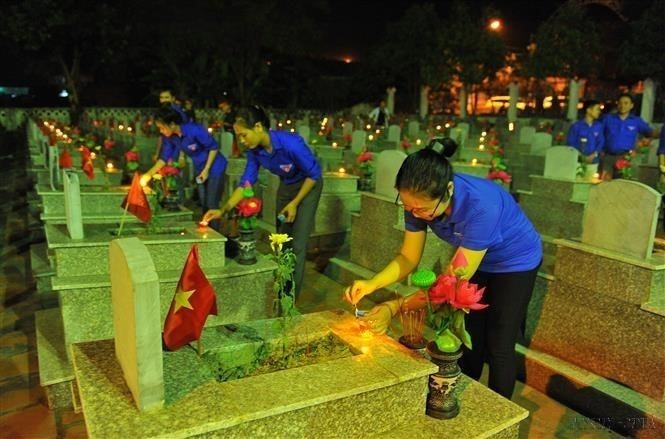  Des membres de l’UJCH et jeunes du district de Yen Mo allument des bougies pour rendre hommage aux héros morts pour la Patrie au cimetière des Morts pour la Patrie du district de Yen Mo, province de Ninh Binh (Nord). Photo: VNA