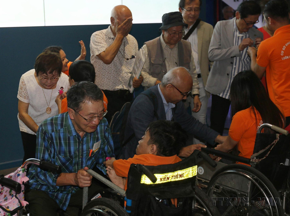  Des enfants du village Hoa Binh (Paix) et des victimes de l'agent orange/dioxine offrent des cadeaux de souvenir à des délégués japonais lors d'une exposition de photos sur les victimes de la guerre au Japon et au Vietnam. Photo : VNA