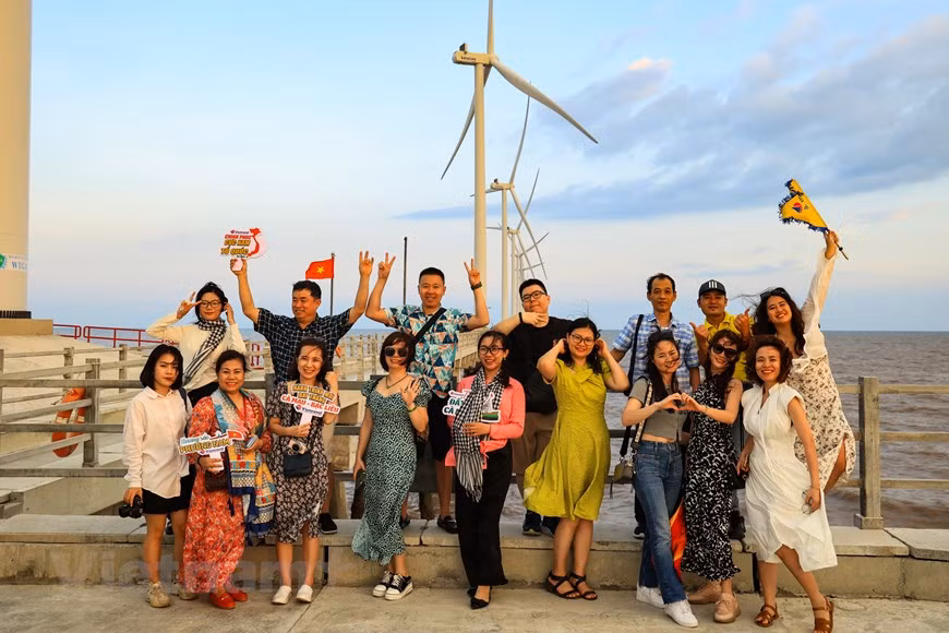  Un groupe de touristes profite du coucher de soleil sur le champ éolien. Photo : Vietnamplus 