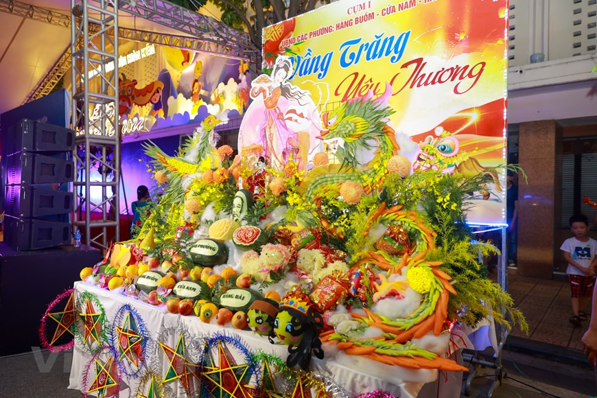 Un “mâm cỗ Trung thu" (table des victuailles de la Fête de la Mi-Automne) des quartiers de l’arrondissement de Hoan Kiem sont savamment préparés et agencés, prêts à accueillir les enfants.Traditionnellement, à cette occasion, les enfants masqués portant des lanternes font le tour du "mâm cỗ Trung thu", qui présente généralement différentes sortes de fruits et de gâteaux de lune (“bánh Trung thu” en vietnamien) et est placé au milieu de la cour ou de la maison. Ils chantent et participent aux danses de la licorne aux sons des tambourins. Une véritable ambiance de fête se répand au même moment à travers tout le pays. Photo: VietnamPlus